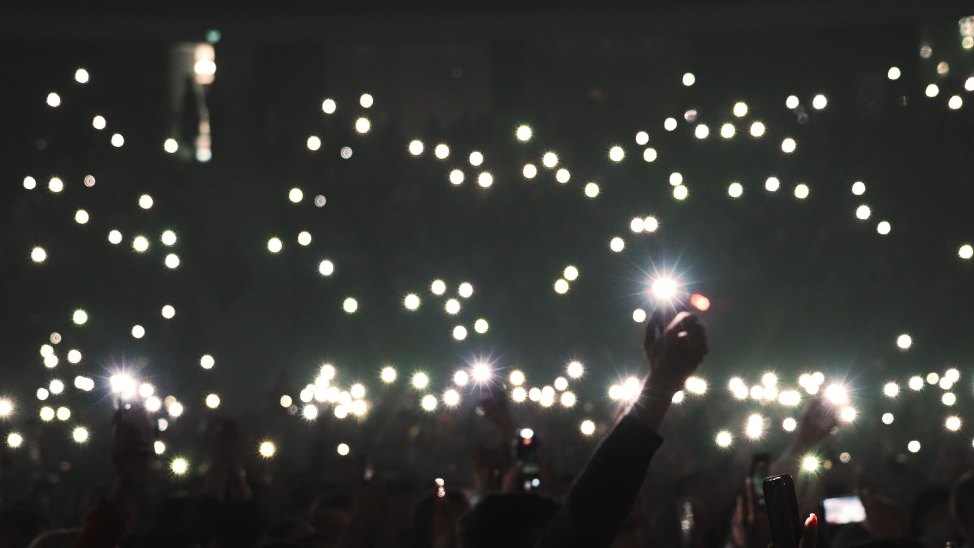 Many people waving phone flash light. Music concert atmosphere. Fans crowd enjoy